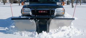 zoomed in picture of a plow connected to a truck plowing the snow
