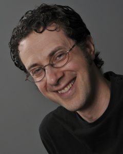 young man with rounded glasses smiling