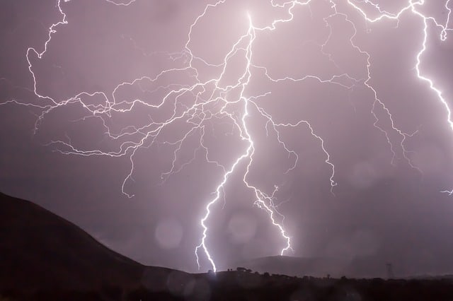 A lighting storm full of bright white, glowing,  thin lightning tendrils is shown in the sky.