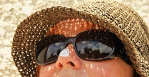 Women wearing a hat, glasses, and sunscreen outdoors 